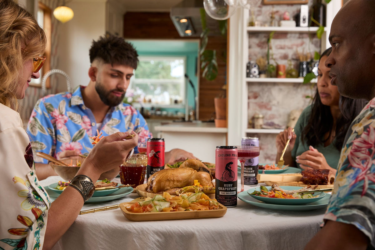 a group of people sitting down to a thanksgiving dinner, drinking Cycling Frog seltzers