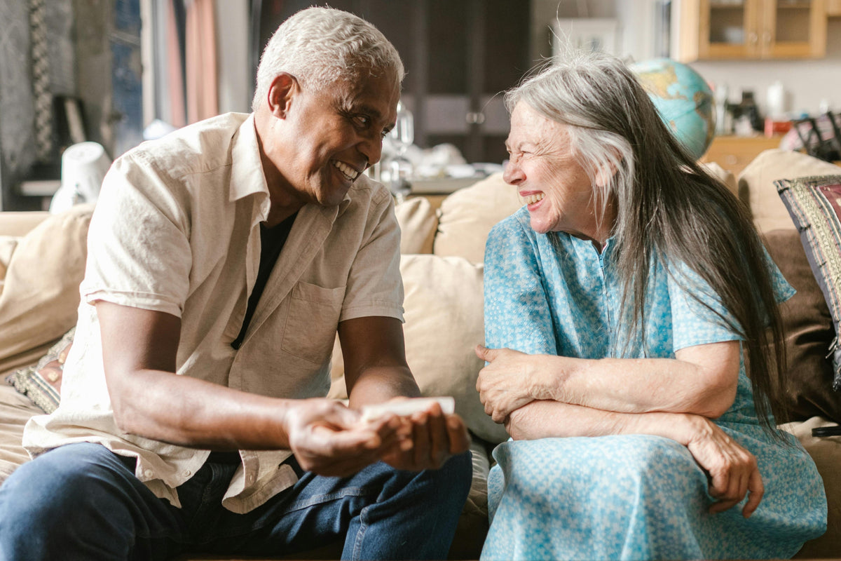 older couple sitting on couch laughing and making eye contact